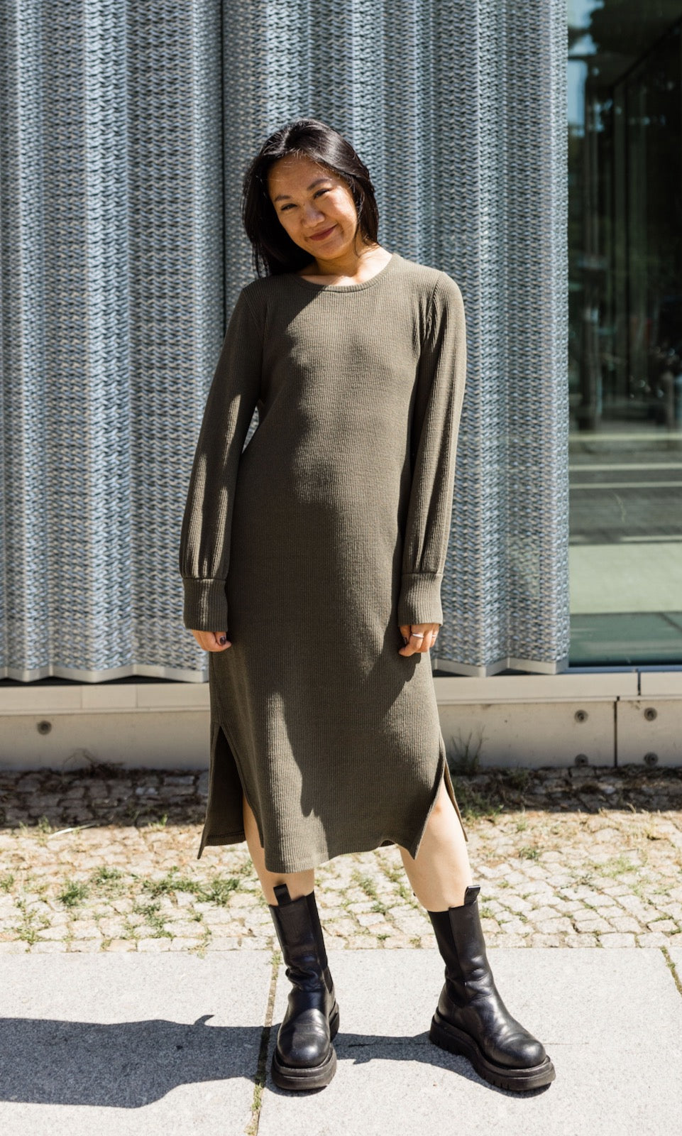 Strick Stillkleid Jules in grün olive mit Stiefeln frontal vor Fenster