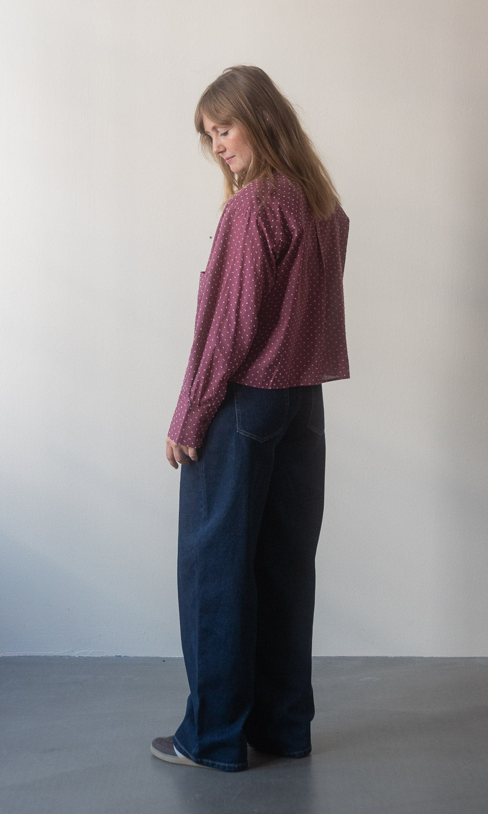 Baggy Jeans in dunkelblau von abricot coco in Seitenansicht. Kombiniert mit rot-weiß gepunkteter Bluse.