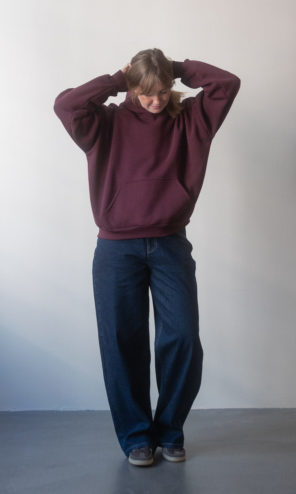 Baggy Jeans in dunkelblau von abricot coco in Vorderansicht. Kombiniert mit rotem Hoodie.