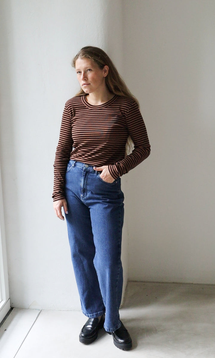Langarm Stillshirt Zoe in braun gestreift kombiniert mit blauer Jeans und schwarzen Schuhen vor grauer Wand von vorne Blick seitlich
