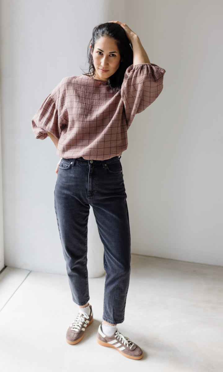 Mom Fit Jeans in schwarz aus Bio-Baumwolle kombiniert mit brauner Musselin-Bluse und braunen Sneakers für den lässig-schicken Look.