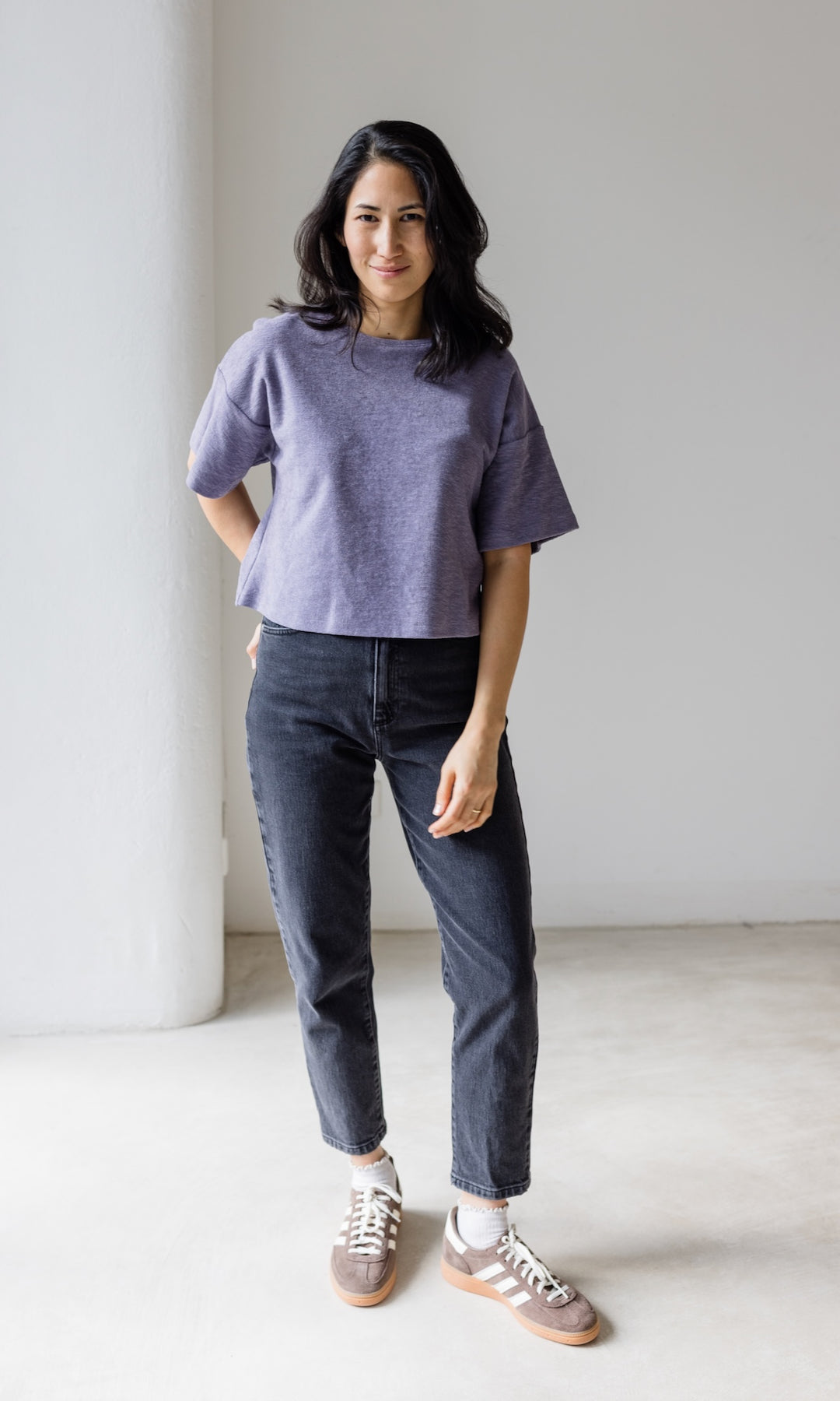 Mom Fit Jeans in schwarz aus Bio-Baumwolle kombiniert mit fliederfarbenen Shirt und braunen Sneakers