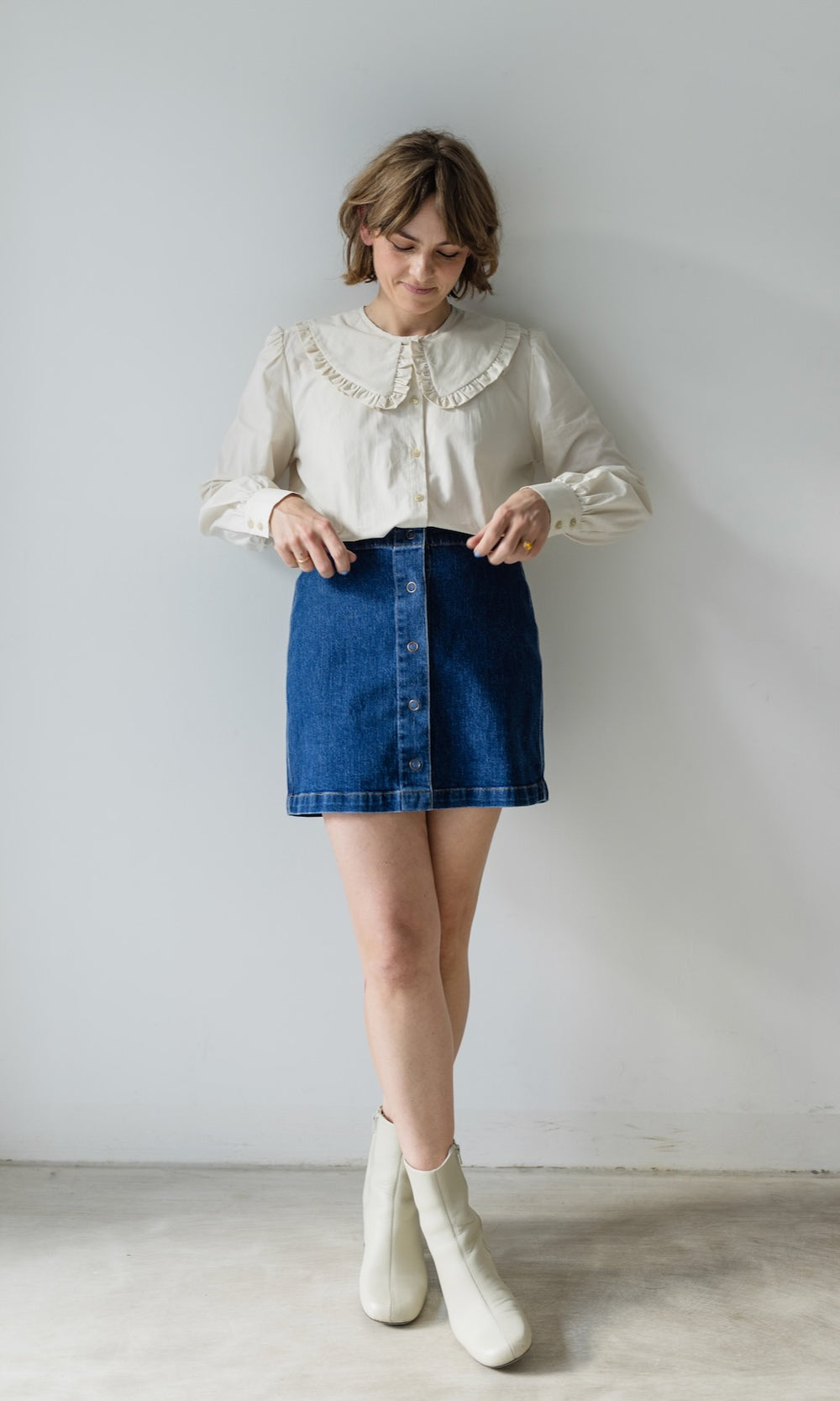 Jeans Minirock in denim blau mit Knöpfen aus Bio-Baumwolle kombiniert mit heller Bluse und hellen Stiefeln