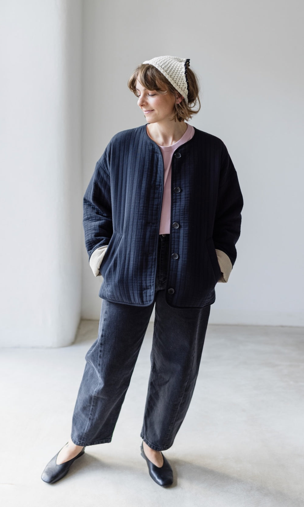 Leichte Oversized Steppjacke Yumiko in schwarz kombiniert mit T-Shirt in rosé, schwarzer Barrel Jeans und schwarzen Loafers - Outfit für einen entspannten Städtetrip