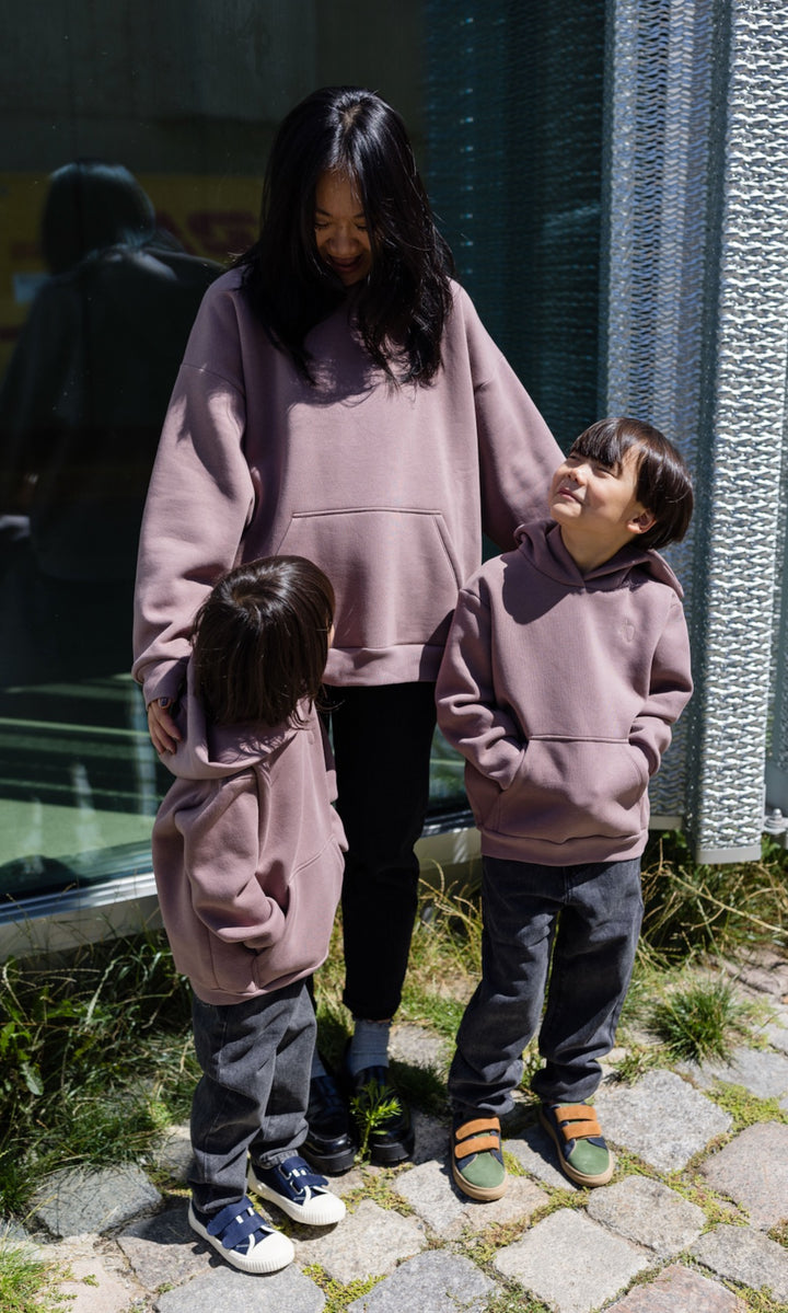 Still Hoodie in aubergine rot stehend mit Frau und zwei Kindern alle mit Still-Hoodie Blick zueinander