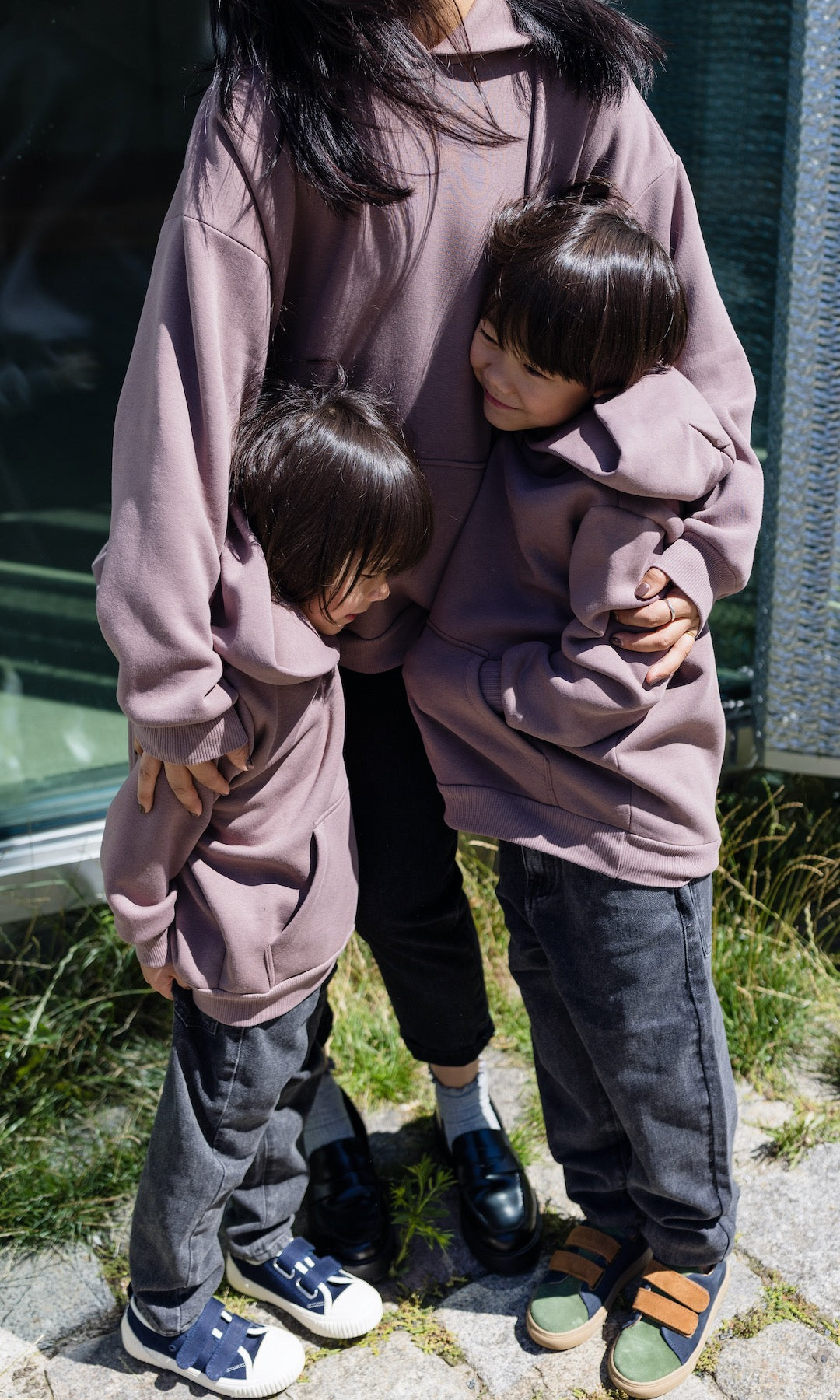 Still Hoodie in aubergine rot stehend mit Frau und zwei Kindern alle mit Still-Hoodie zusammen stehend