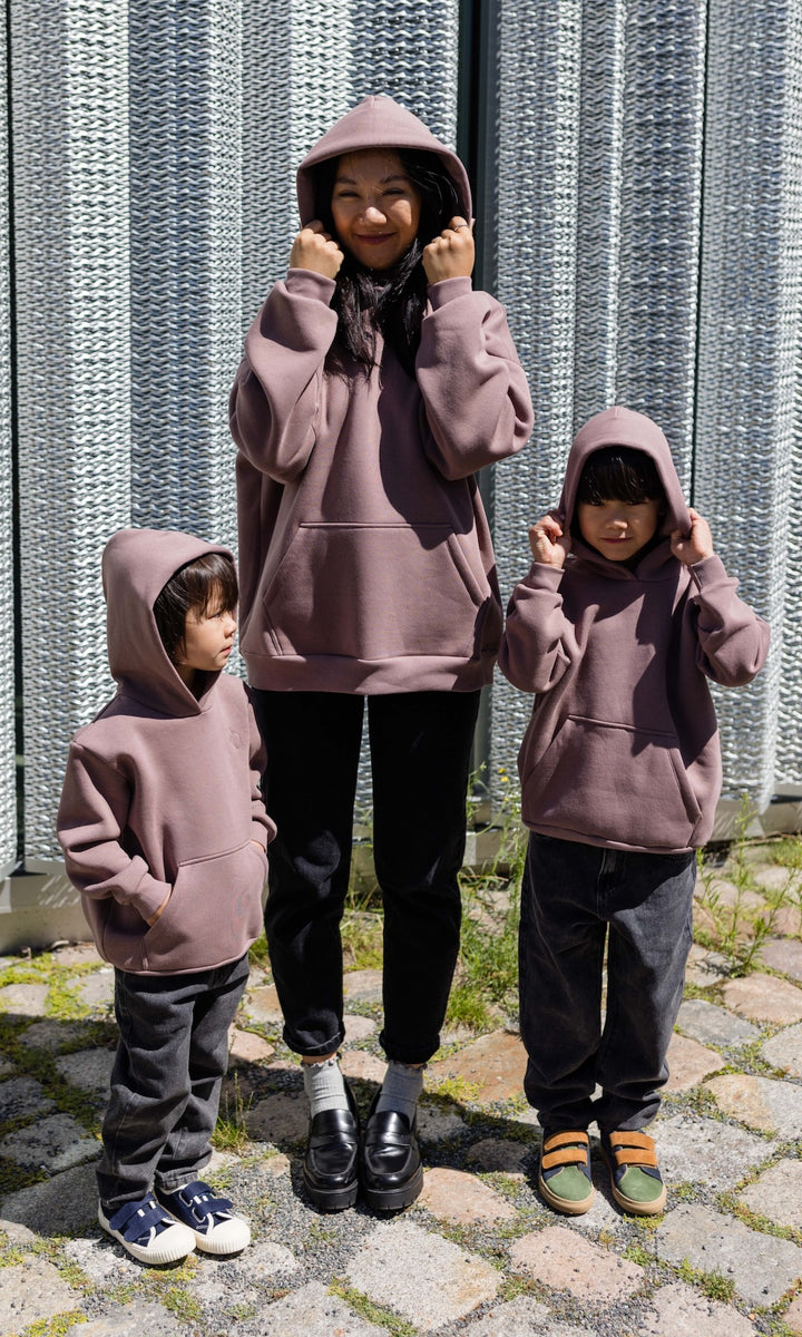 Still Hoodie in aubergine rot stehend mit Frau und zwei Kindern alle mit Still-Hoodie Kapuze auf Kopf Blick nach vorne