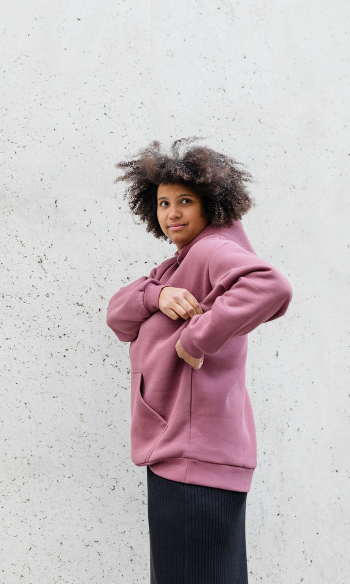 Still Hoodie in feige rosa vor grauer Wand kombiniert mit schwarzem Rock seitlich Blick seitlich