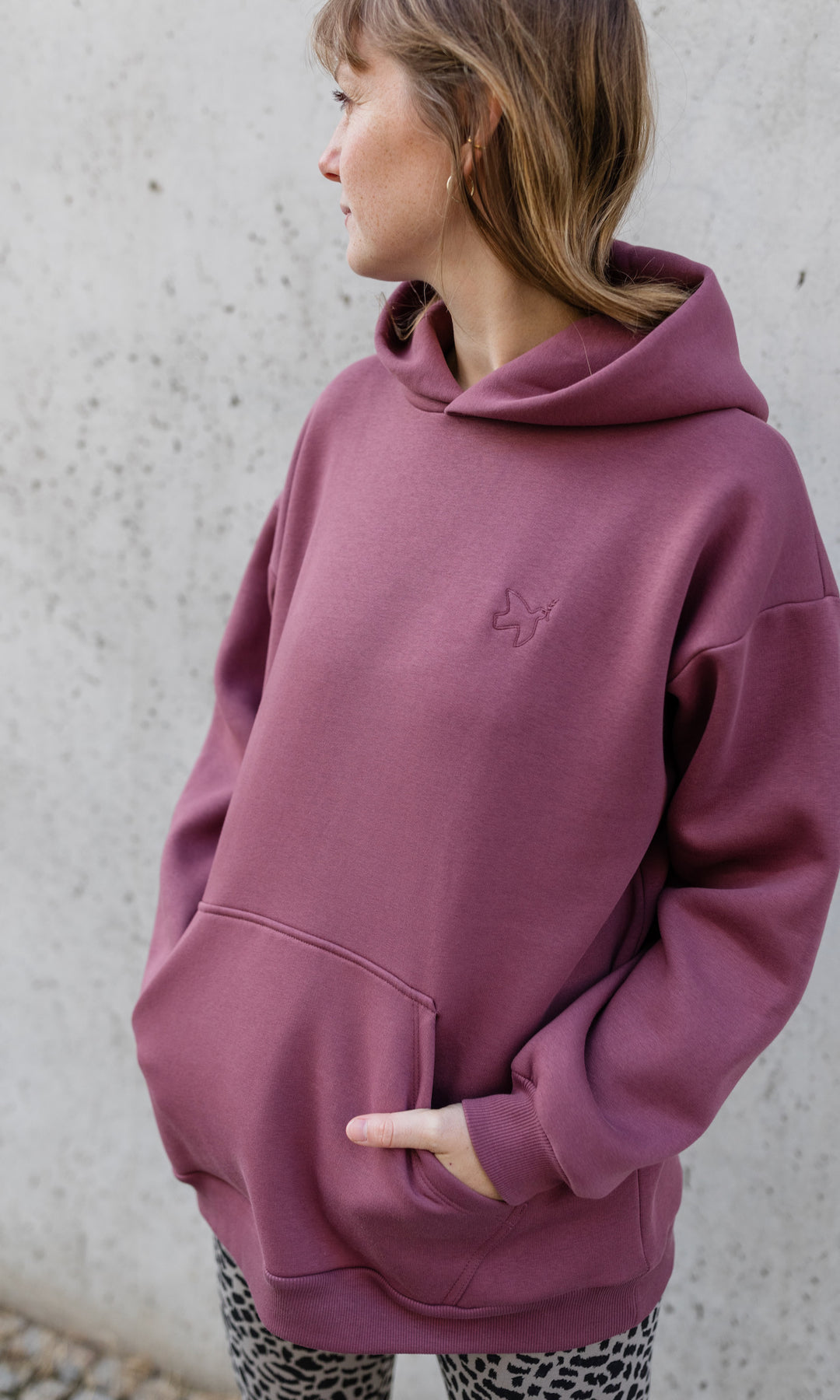 Stillhoodie in feige rosa vor grauer Wand kombiniert mit Leo Leggings seitlich Blick seitlich