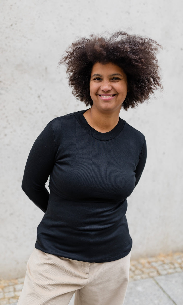 Langarm Stilloberteil Cléo mit Rollkragen in schwarz kombiniert mit heller Hose von vorne Blick gerade lächelnd