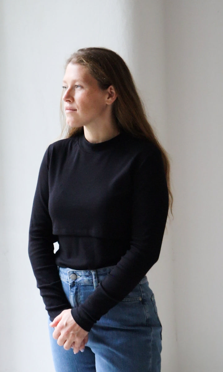 Langarm Stillshirt Cléo mit Rollkragen in schwarz kombiniert mit hellblauer Jeans vor grauer Wand seitlich Blick gerade