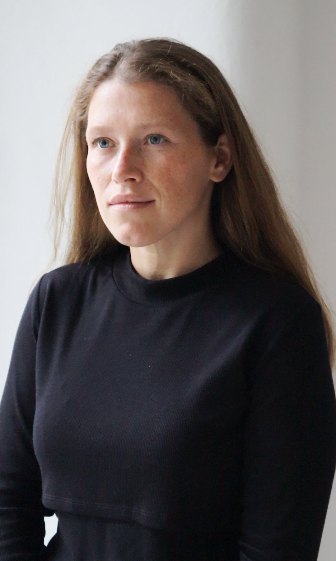 Longsleeve Stillshirt Cléo mit Rollkragen in schwarz vor grauer Wand seitlich Blick gerade