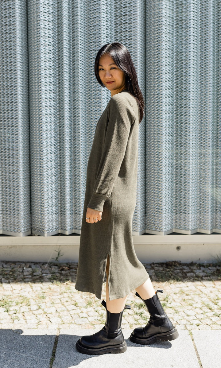 Strick Stillkleid Jules in grün olive mit Stiefeln seitlich vor Fenster