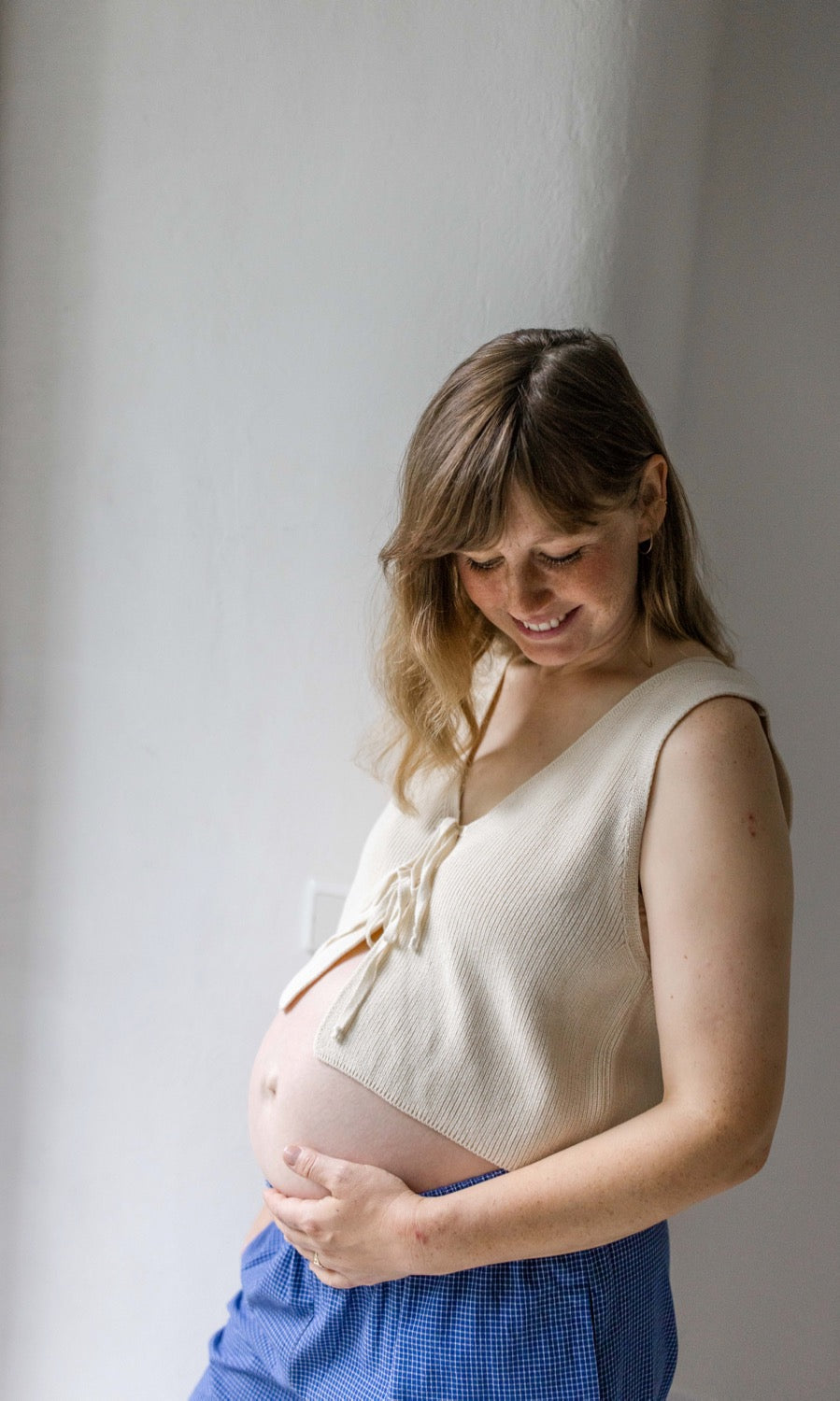 Detailansicht elastischer Unterbauchbund. Umstandshose Ivy Culotte in blau kombiniert mit hellem Baumwoll-Strickpullunder.