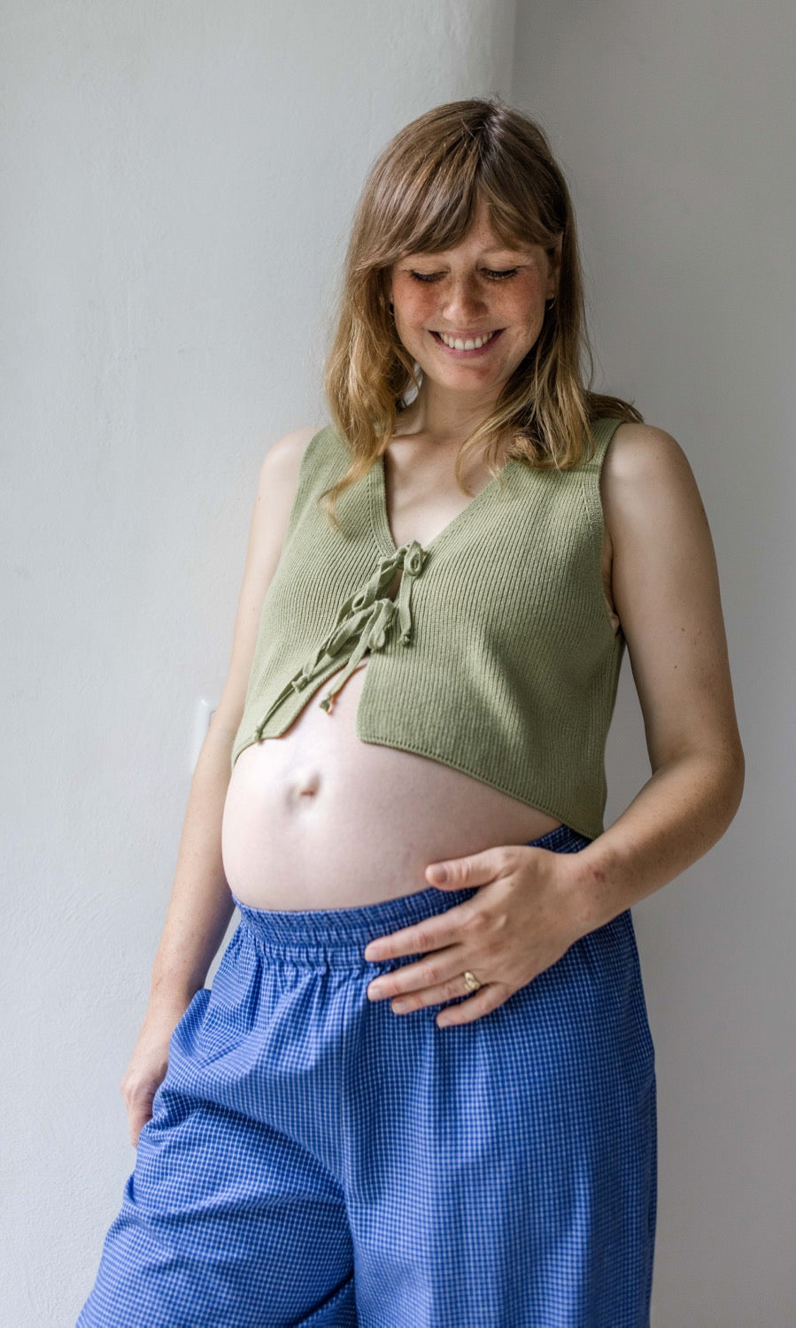 Detailansicht elastischer Unterbauchbund. Umstandshose Ivy Culotte in blau kombiniert mit grünem Baumwoll-Strickpullunder.