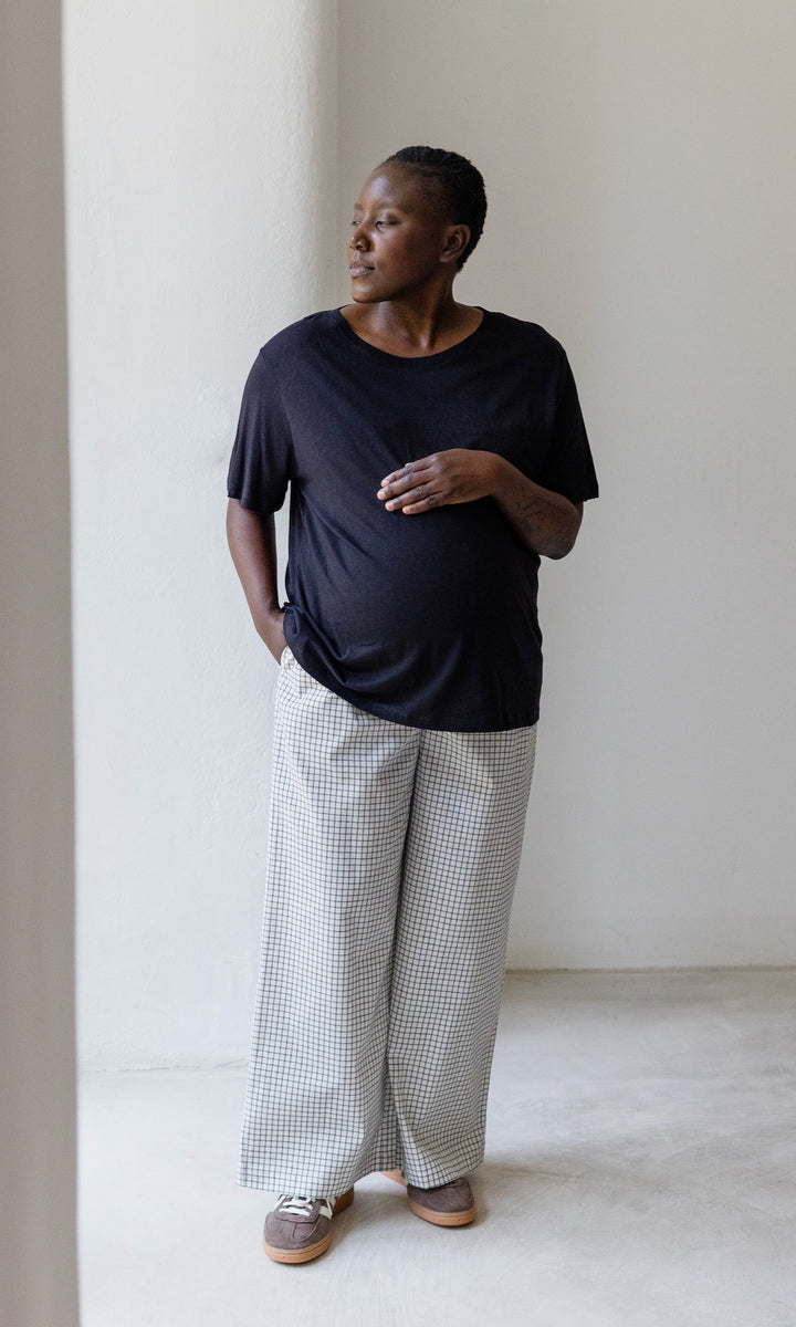 Umstandshose Ivy Culotte in karo weiß kombiniert mit dunkelblauem T-Shirt und braunen Sneakers. Vorderansicht.