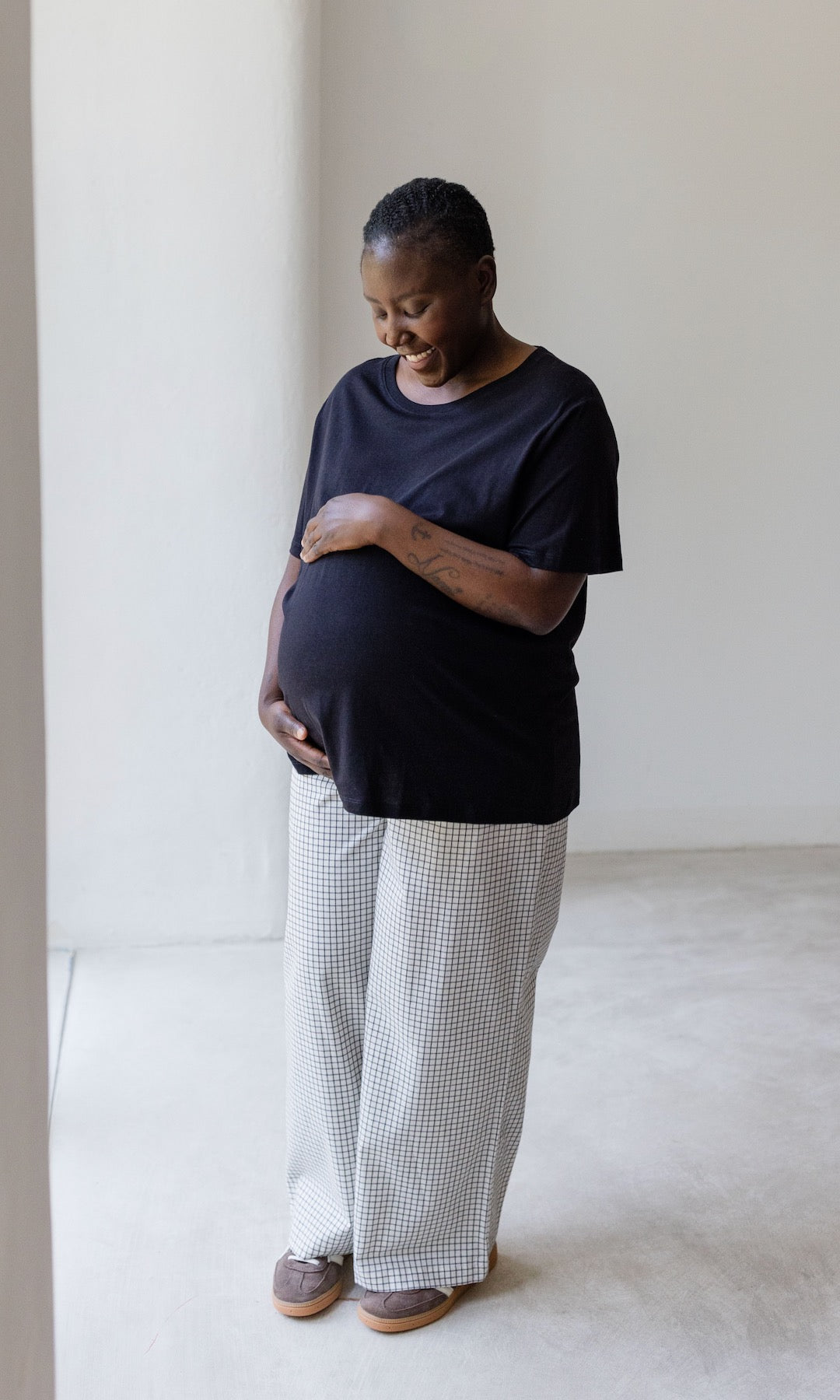 Umstandshose Ivy Culotte in karo weiß kombiniert mit dunkelblauem T-Shirt und braunen Sneakers. Seitenansicht schräg.