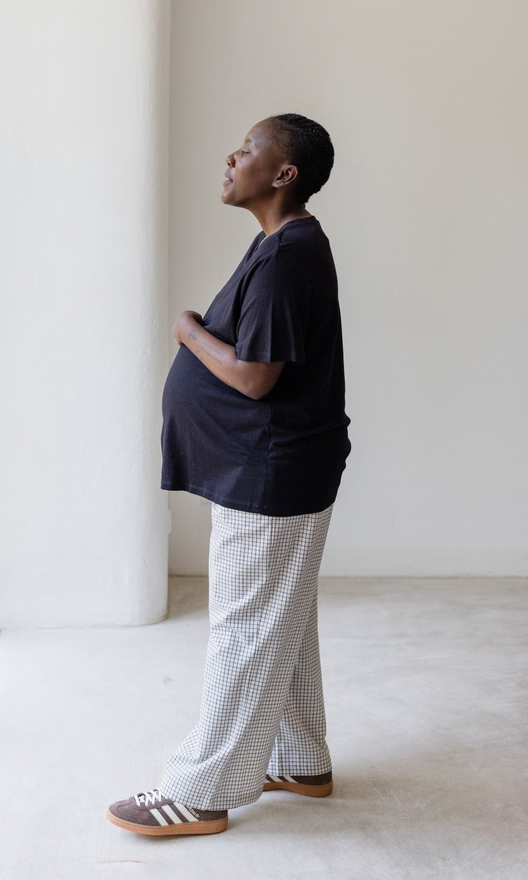 Umstandshose Ivy Culotte in karo weiß kombiniert mit dunkelblauem T-Shirt und braunen Sneakers. Seitenansicht.