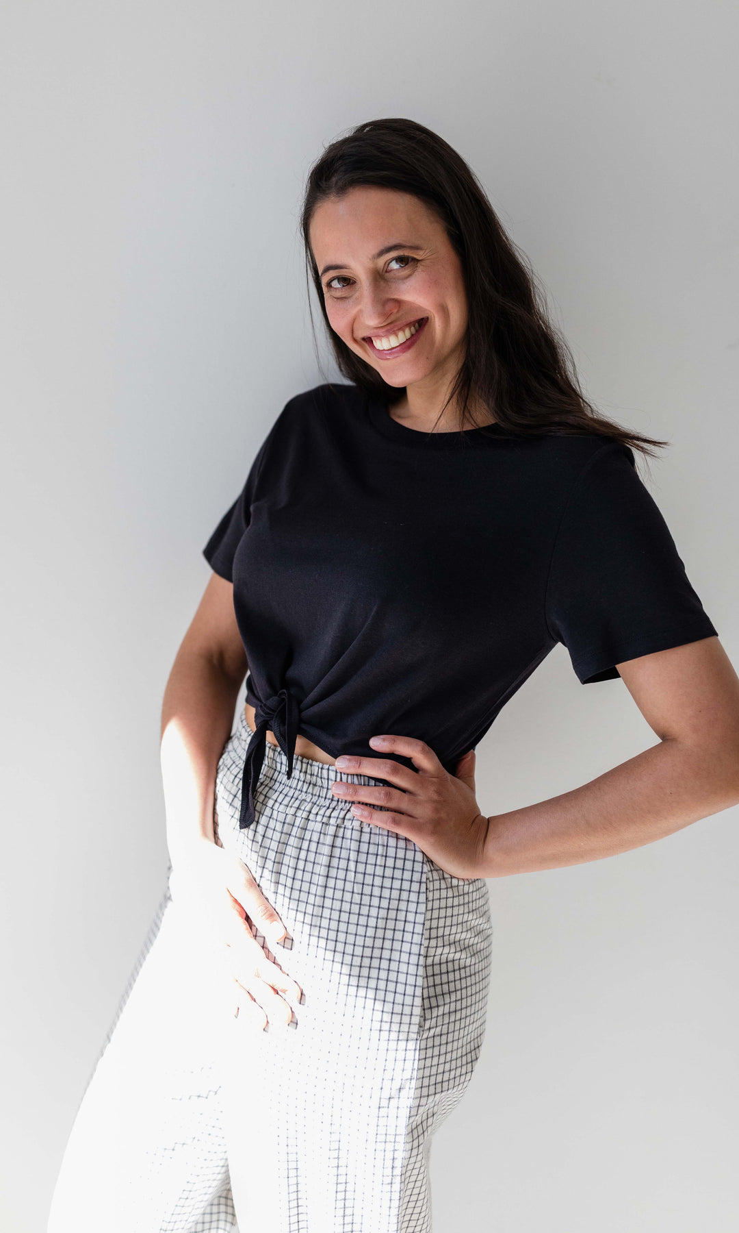 Umstandshose Ivy Culotte in karo weiß kombiniert mit dunkelblauem T-Shirt. Ansicht vor heller Wand.