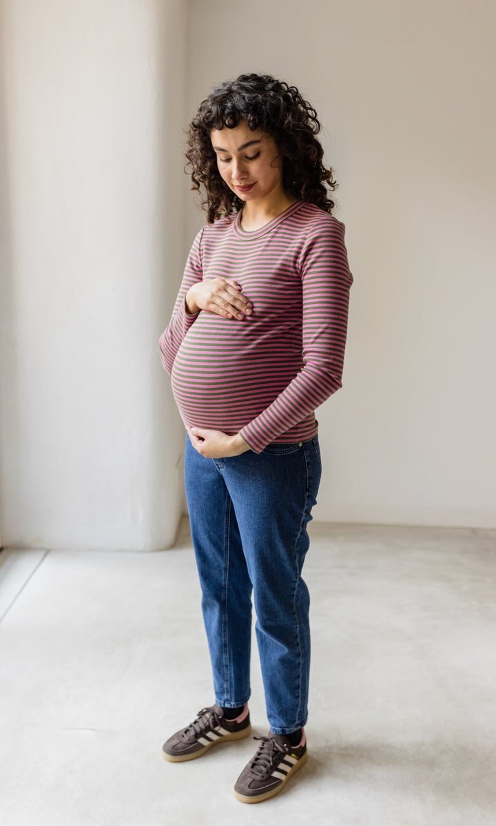 Umstandsjeans im Mom Fit Look in dunkelblau kombiniert mit gestreiftem braun rotem Langarmhirt und braunen Sneakers seitlich Blick auf Babybauch