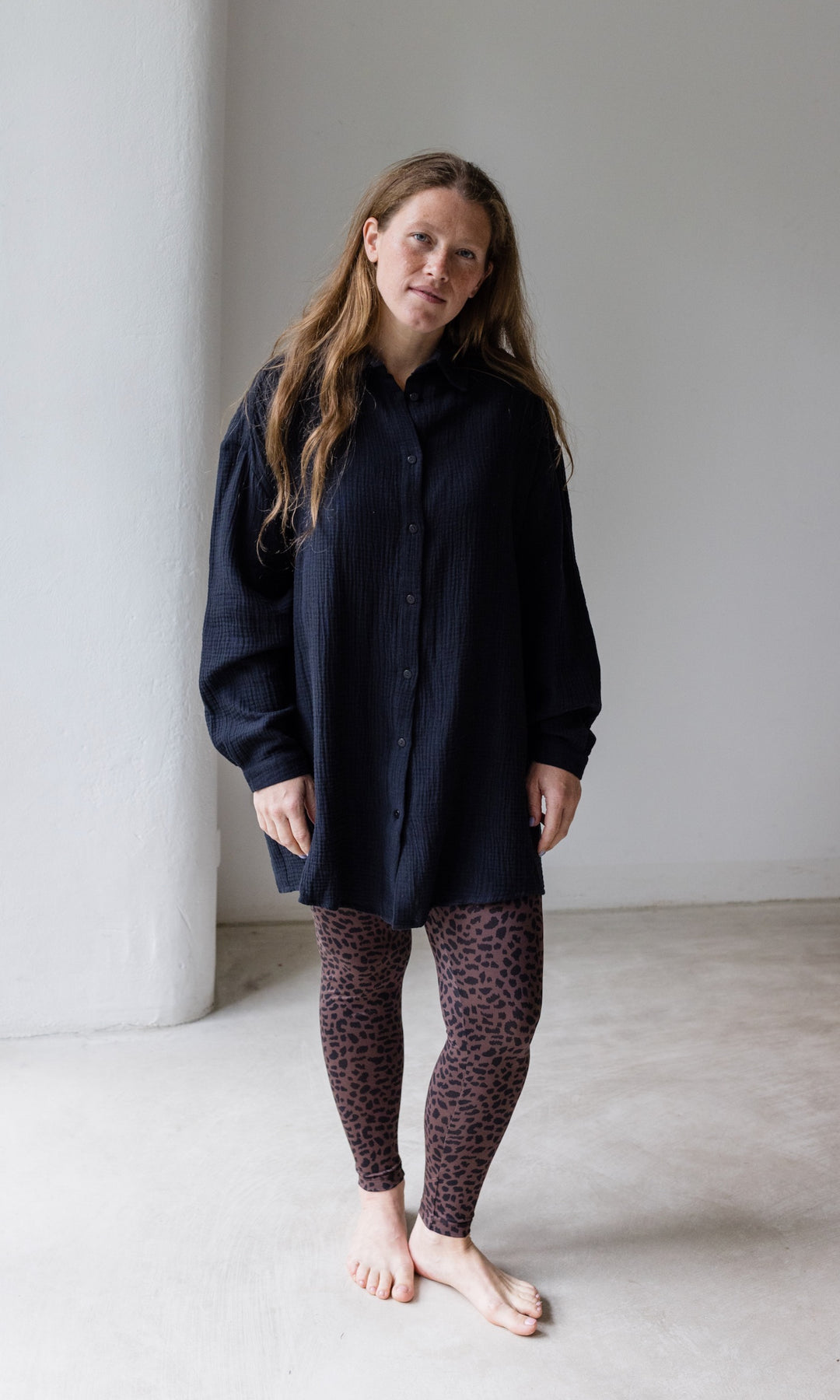 Umstandsleggings braun leo Print mit schwarzem Musselin Hemd vor heller Wand Blick nach vorne