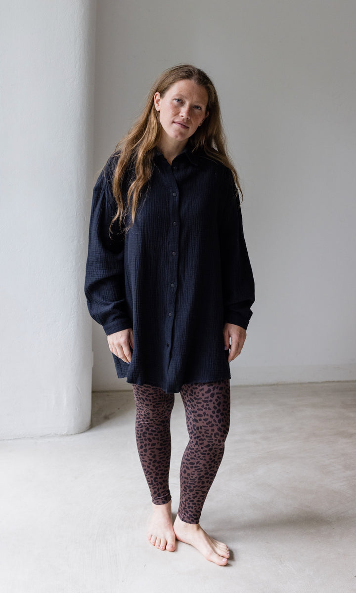 Umstandsleggings braun leo Print mit schwarzem Musselin Hemd vor heller Wand Blick nach vorne