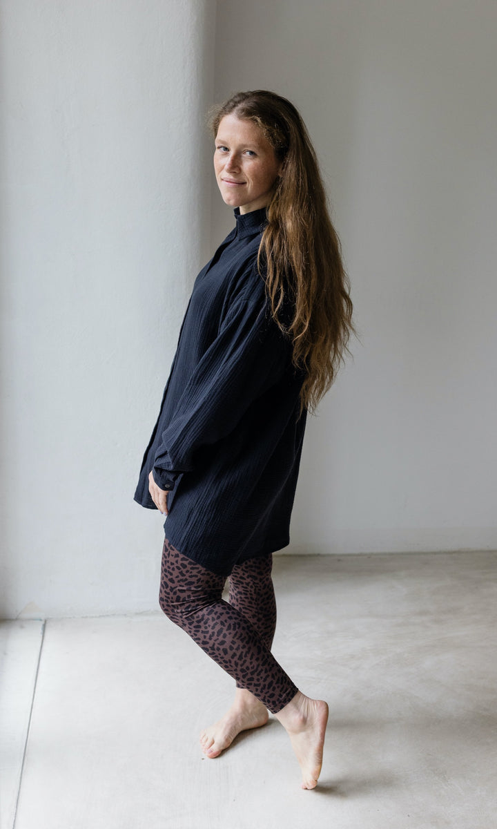 Umstandsleggings braun leo Print mit schwarzem Musselin Hemd seitlich vor heller Wand Blick nach vorne