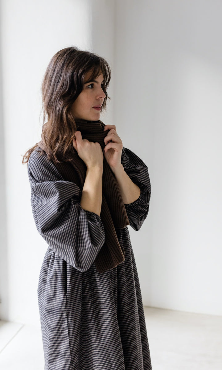 Winter Stillkleid Lovis in karo schwarz mit schwarzen Stiefeln und braunem Schal seitlich