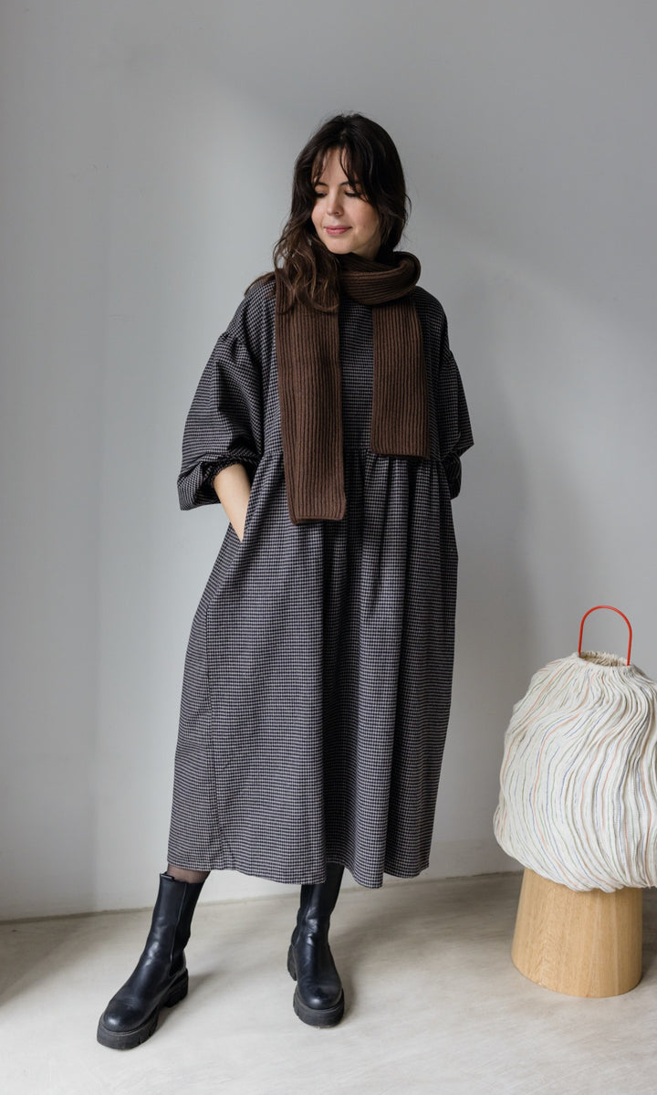 Winter Stillkleid Lovis in karo schwarz mit schwarzen Stiefeln und schwarzem Schal Blick seitlich nach unten