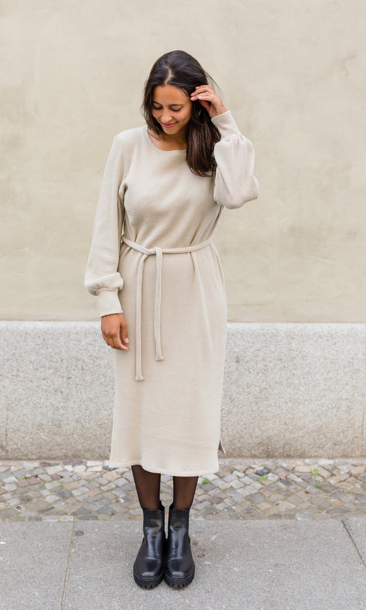 Elegantes Strick Stillkleid Jules in creme beige im festlichen Look mit Strumpfhose und Stiefeln Ansicht frontal vor heller Wand Blick nach unten