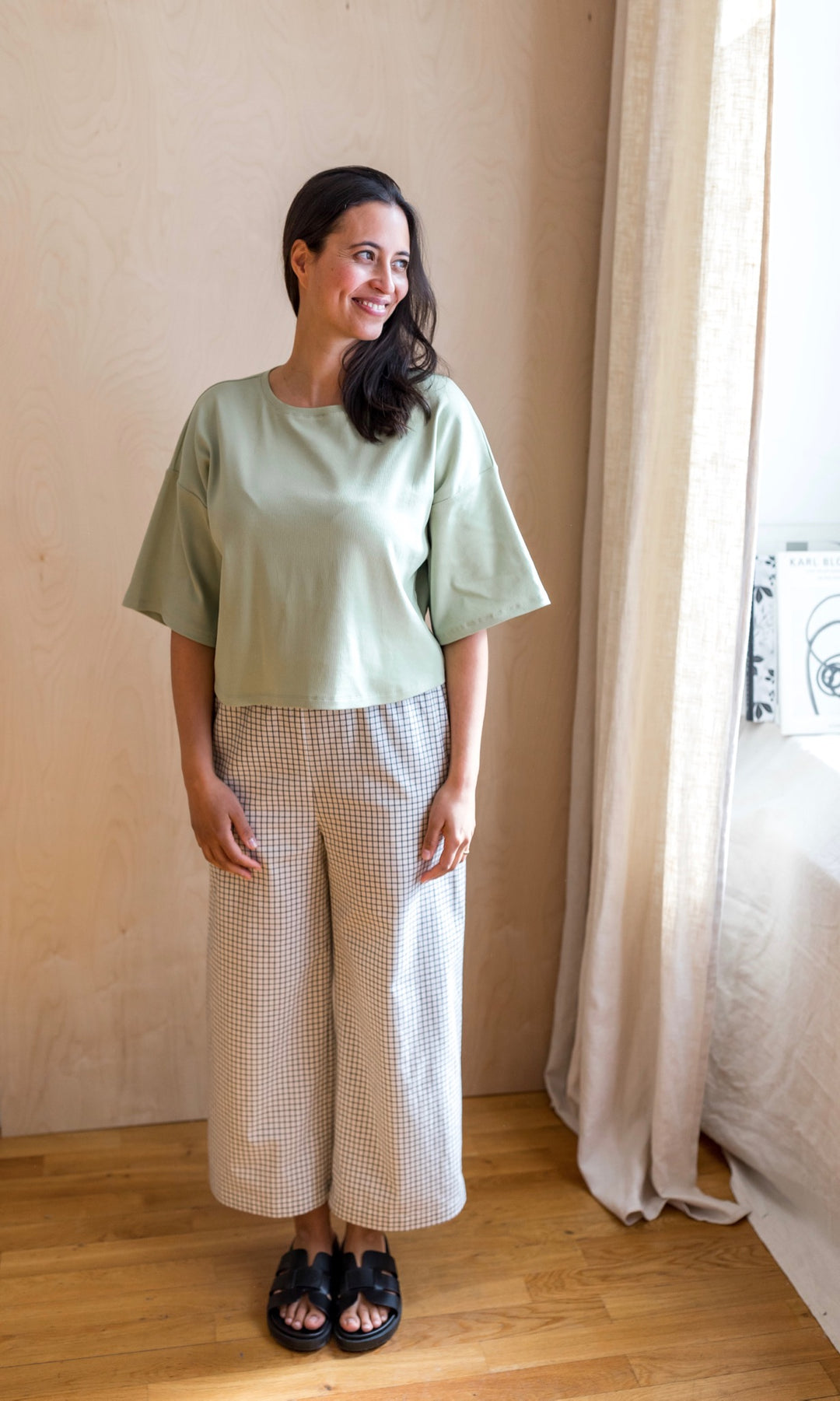 Umstandshose Ivy Culotte in karo weiß im Look kombiniert mit hellgrünem T-Shirt und schwarzen Sandalen. Vorderansicht.